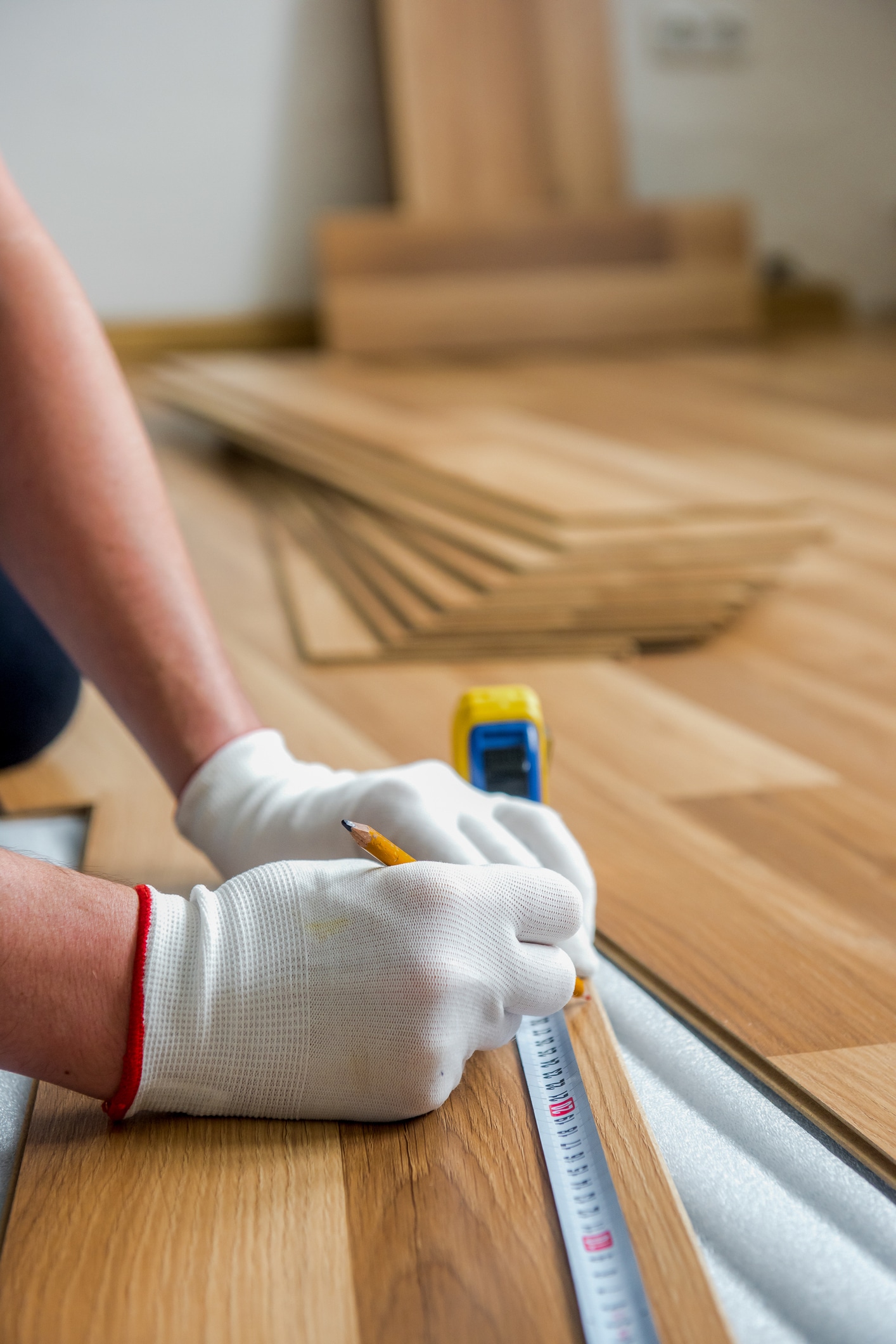 The worker is laying laminate wood flooring in the room - repair and finishing works - Finplex Construction